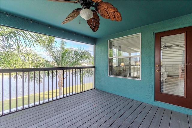 deck with a water view and ceiling fan