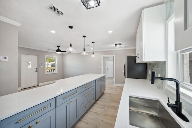 kitchen featuring visible vents, light countertops, a sink, and ornamental molding