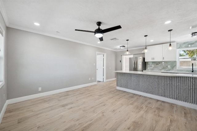 kitchen with light countertops, ornamental molding, and freestanding refrigerator