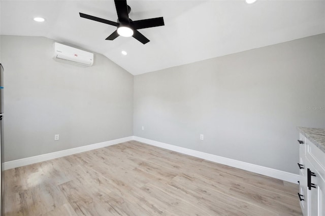 spare room with lofted ceiling, light wood finished floors, baseboards, and a wall mounted AC