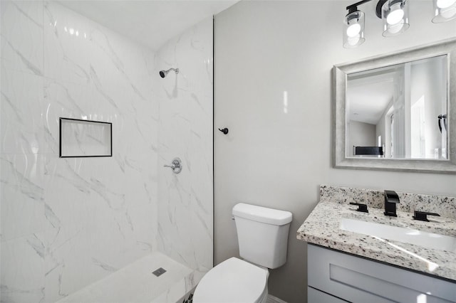 full bath featuring toilet, a marble finish shower, and vanity