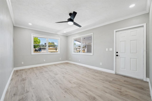 empty room with baseboards, light wood finished floors, and crown molding