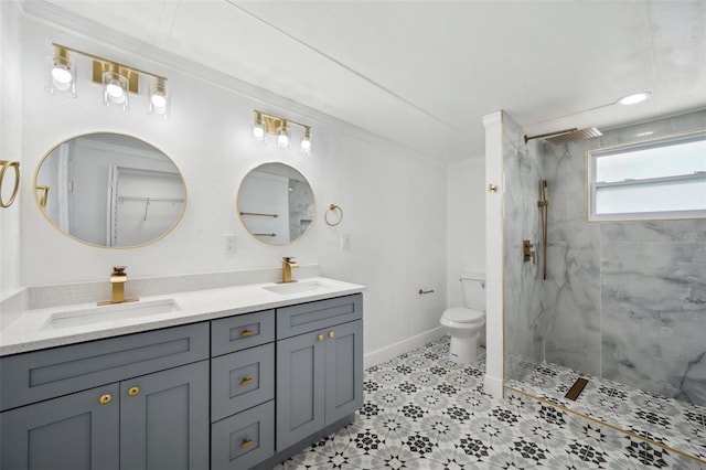 bathroom featuring a marble finish shower, a sink, toilet, and double vanity