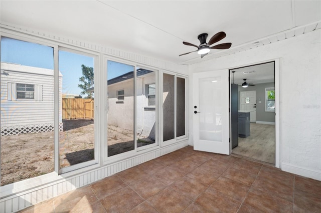 unfurnished sunroom featuring a ceiling fan