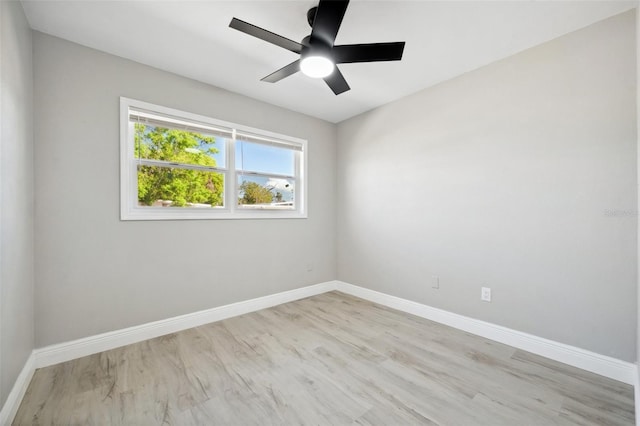 spare room with a ceiling fan, light wood-type flooring, and baseboards