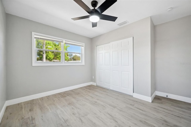 unfurnished bedroom featuring a closet, visible vents, baseboards, and wood finished floors