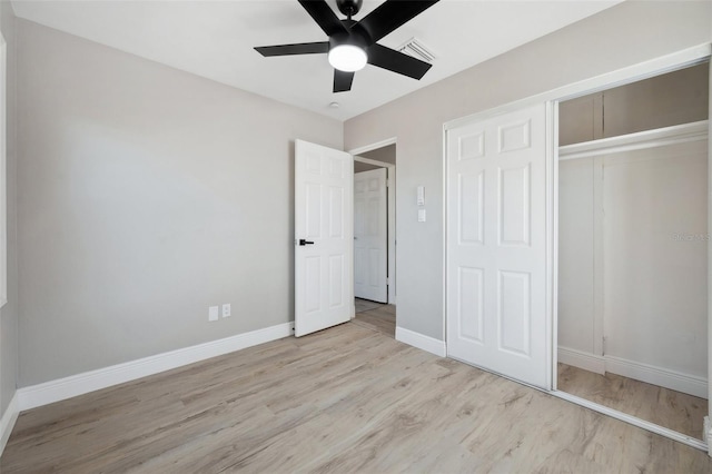 unfurnished bedroom featuring a closet, visible vents, a ceiling fan, wood finished floors, and baseboards