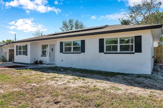 single story home featuring solar panels, fence, and stucco siding