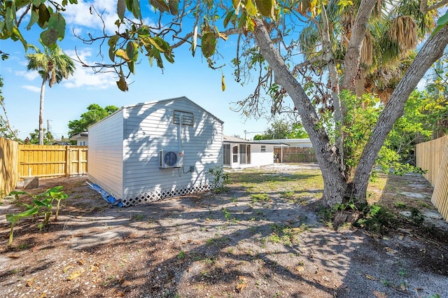 rear view of property with an outbuilding, ac unit, and a fenced backyard