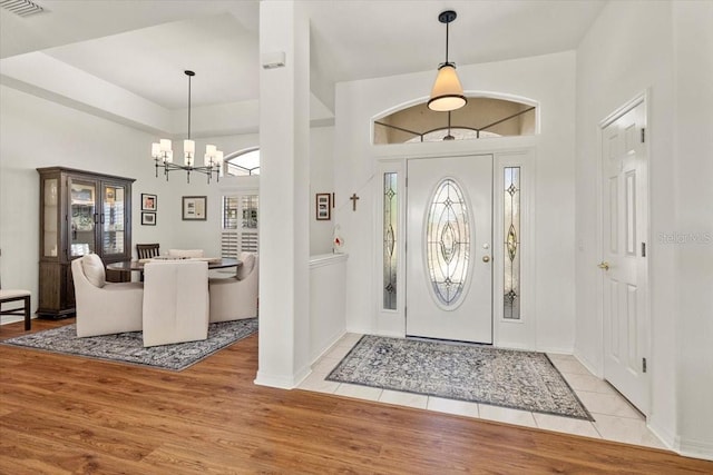 foyer with light hardwood / wood-style floors, a chandelier, and a high ceiling