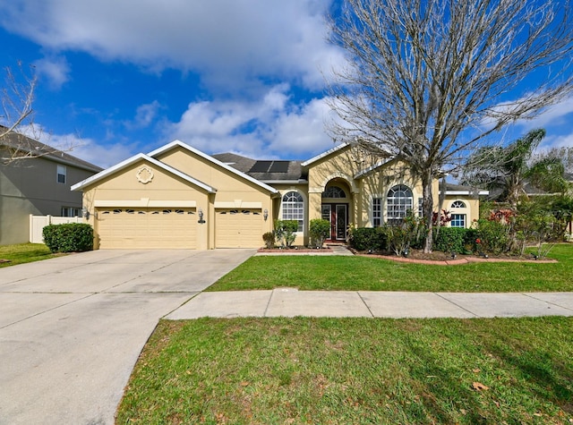 ranch-style home featuring a garage, a front yard, and solar panels