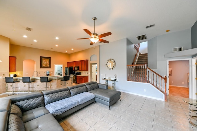 living room featuring light tile patterned floors, sink, and ceiling fan