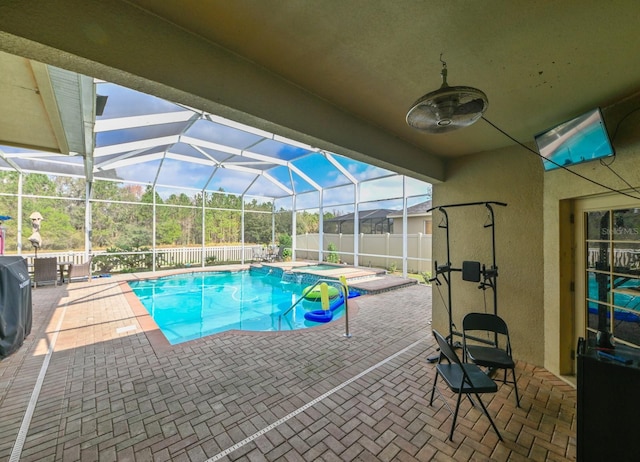 view of pool with a patio area, glass enclosure, and an in ground hot tub