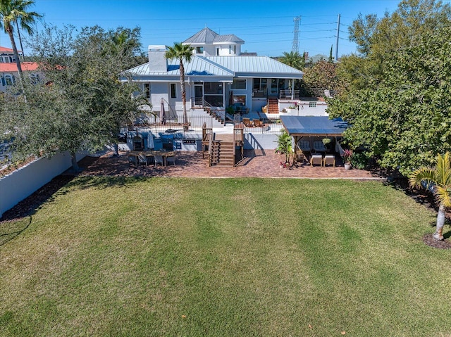 rear view of property featuring metal roof, a lawn, a patio area, and fence