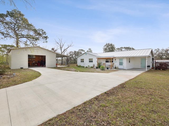 ranch-style home featuring a front yard, a garage, and an outbuilding