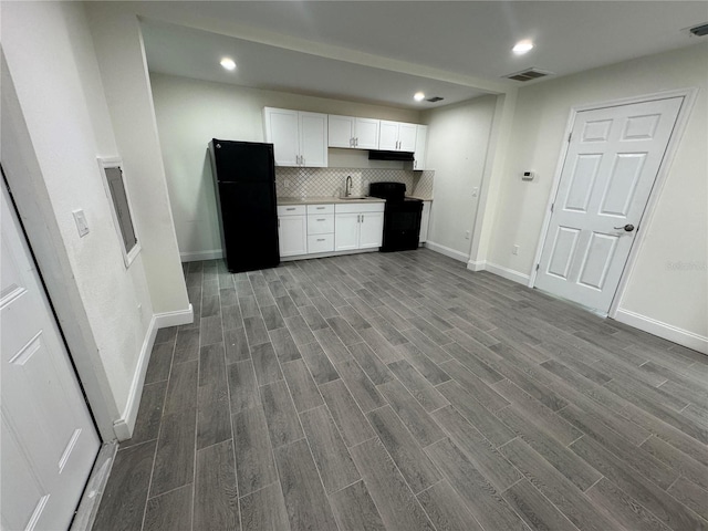 kitchen featuring black refrigerator, white cabinetry, sink, and decorative backsplash