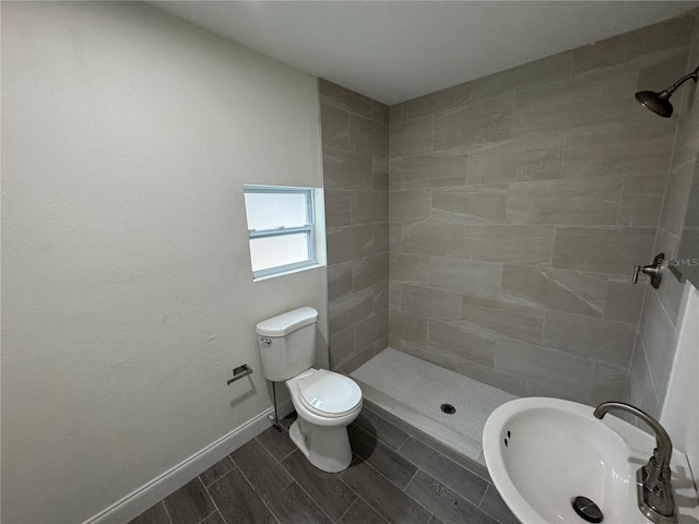 bathroom featuring a tile shower, sink, and toilet