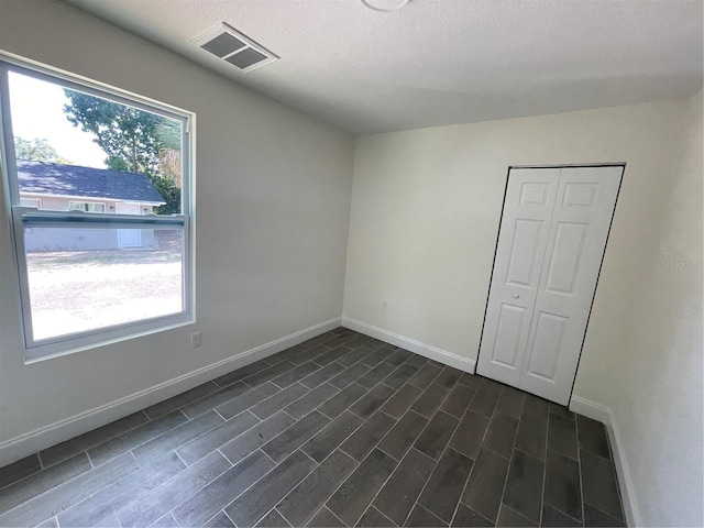 empty room featuring dark hardwood / wood-style floors, a textured ceiling, and a wealth of natural light