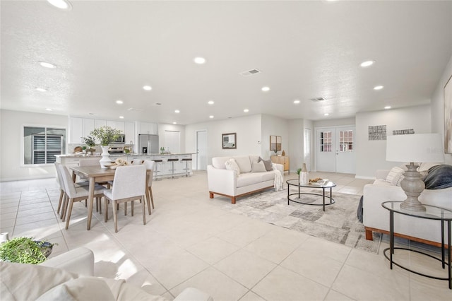 living area with recessed lighting, light tile patterned flooring, visible vents, and a textured ceiling