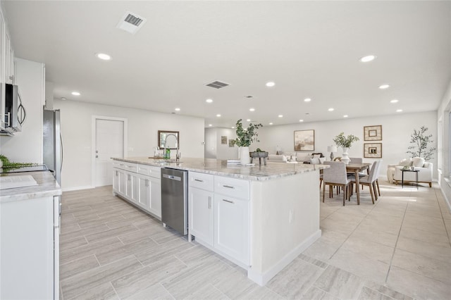 kitchen with visible vents, appliances with stainless steel finishes, a center island with sink, and white cabinets