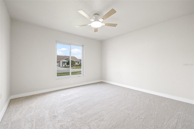 carpeted spare room featuring a textured ceiling, baseboards, and a ceiling fan