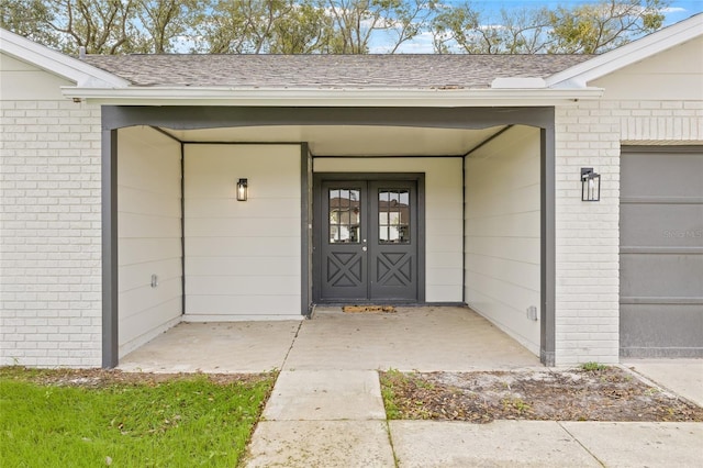 entrance to property featuring a shingled roof and an attached garage