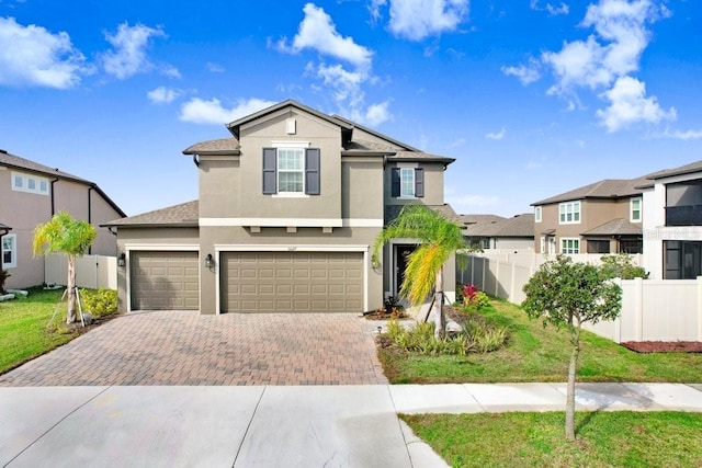 view of front facade featuring decorative driveway, stucco siding, fence, a residential view, and a front lawn