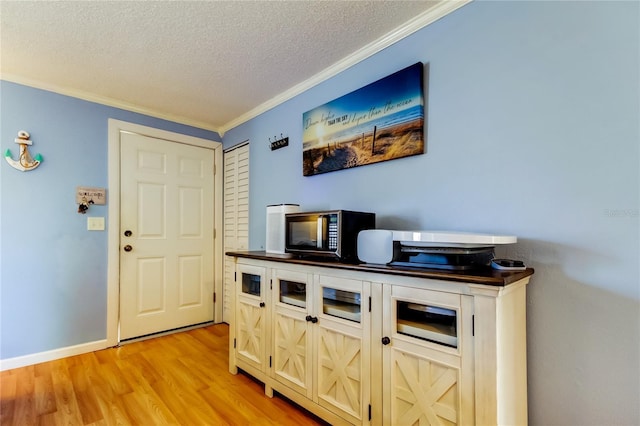 interior space with light hardwood / wood-style flooring, a textured ceiling, and ornamental molding