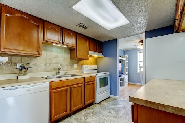 kitchen featuring tasteful backsplash, white appliances, a textured ceiling, ceiling fan, and sink