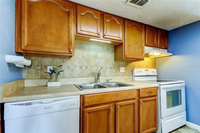 kitchen featuring sink, white appliances, a textured ceiling, and decorative backsplash