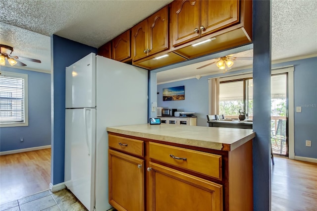 kitchen with a textured ceiling, white fridge, light wood-type flooring, and ceiling fan