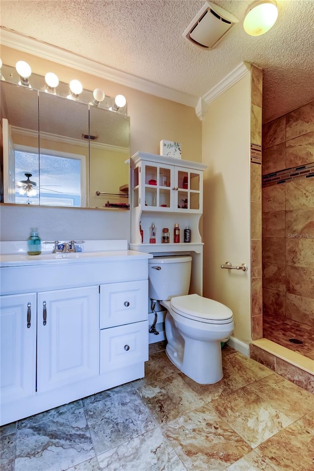 bathroom with ornamental molding, a tile shower, toilet, a textured ceiling, and vanity