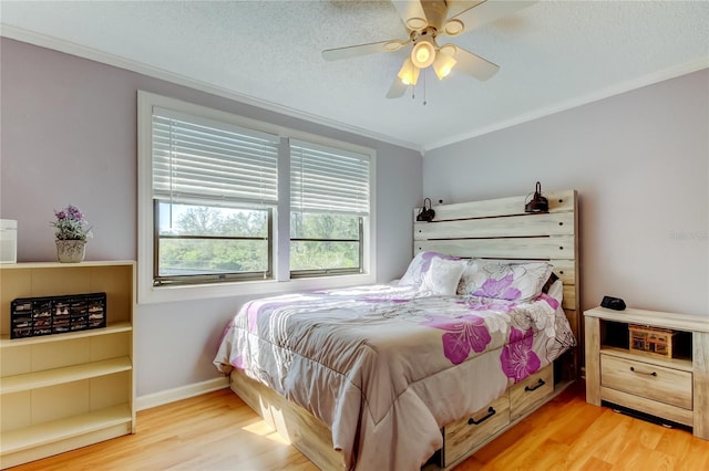 bedroom featuring ceiling fan, light hardwood / wood-style flooring, a textured ceiling, and ornamental molding