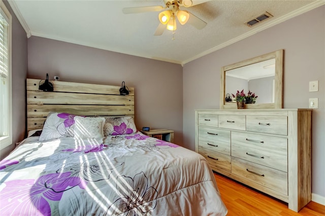 bedroom featuring light wood-type flooring, crown molding, and ceiling fan