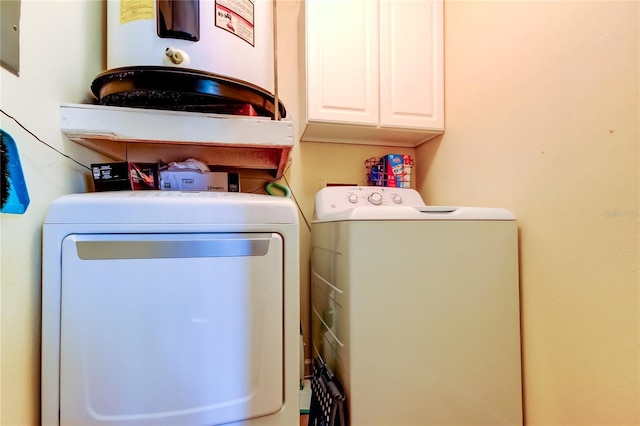 washroom with washer and dryer, water heater, and cabinets