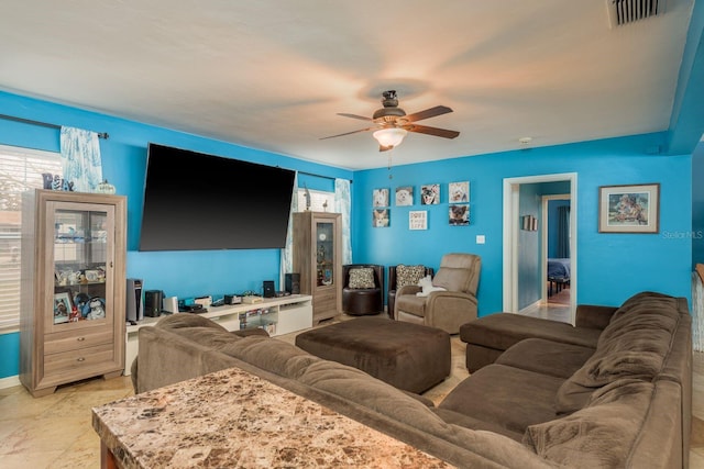 living area with baseboards, plenty of natural light, visible vents, and a ceiling fan