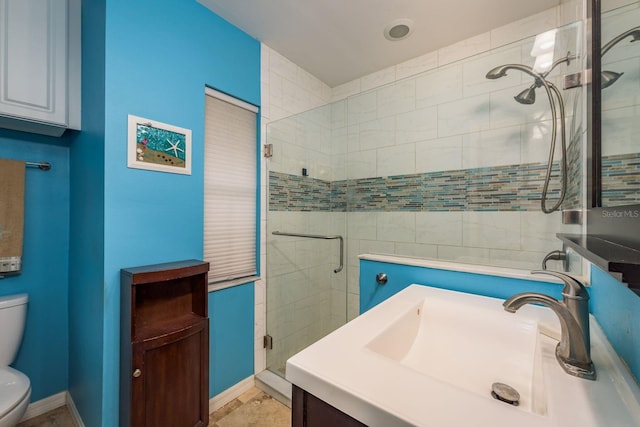 full bath featuring a stall shower, vanity, toilet, and baseboards