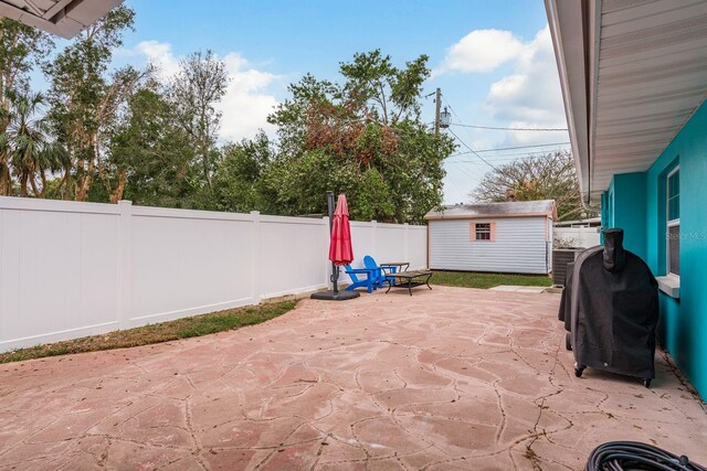 view of patio / terrace featuring an outbuilding, a fenced backyard, a grill, and a shed