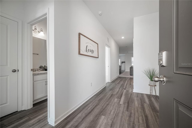 hallway with dark wood finished floors, visible vents, and baseboards