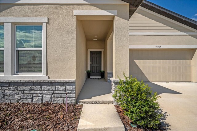 doorway to property featuring stucco siding, driveway, and a garage