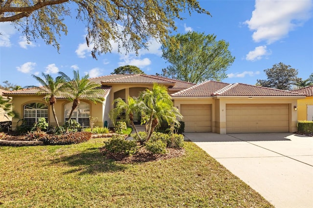 mediterranean / spanish-style house with a front yard, driveway, an attached garage, stucco siding, and a tile roof