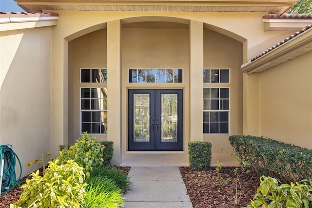 doorway to property with stucco siding, french doors, and a tile roof