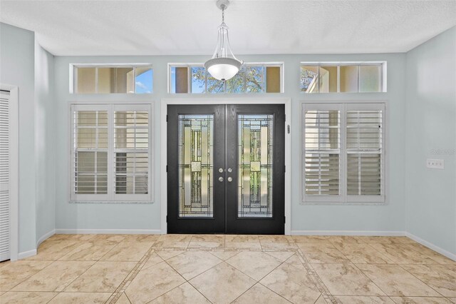 tiled foyer entrance with french doors, baseboards, and plenty of natural light