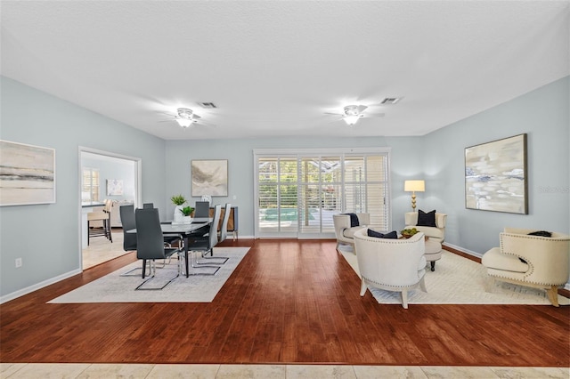 living room with visible vents, ceiling fan, and wood-type flooring