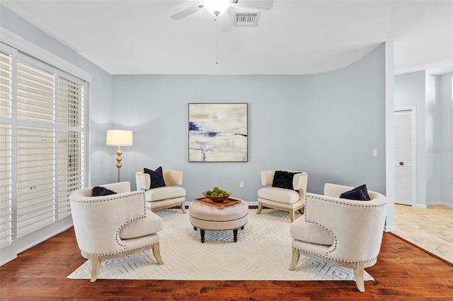 living room with visible vents, baseboards, wood finished floors, and a ceiling fan