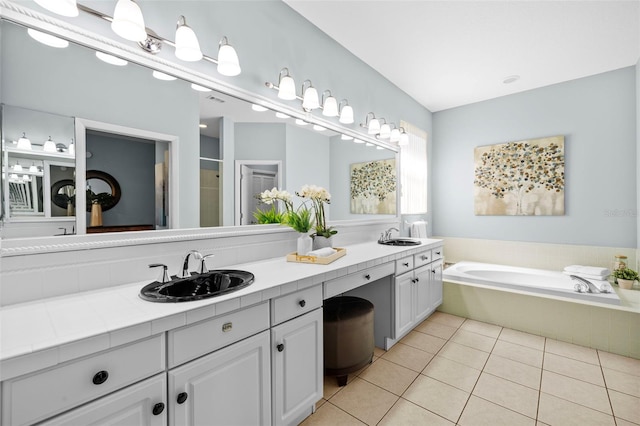 bathroom featuring tile patterned flooring, double vanity, a garden tub, and a sink