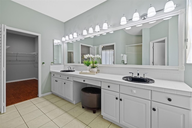 bathroom with a sink, walk in shower, tile patterned floors, and double vanity