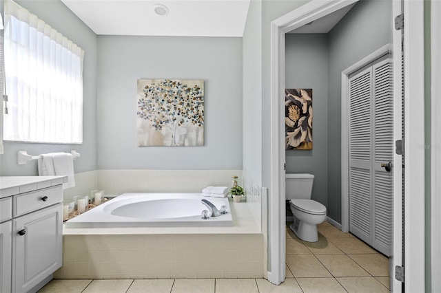 bathroom with vanity, tile patterned flooring, a closet, a garden tub, and toilet