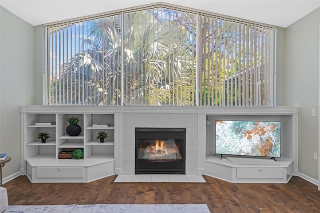 unfurnished living room featuring a tile fireplace, baseboards, and wood finished floors