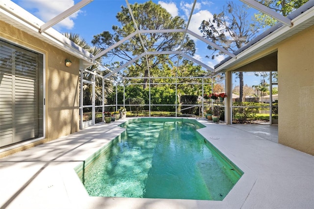 outdoor pool featuring glass enclosure and a patio